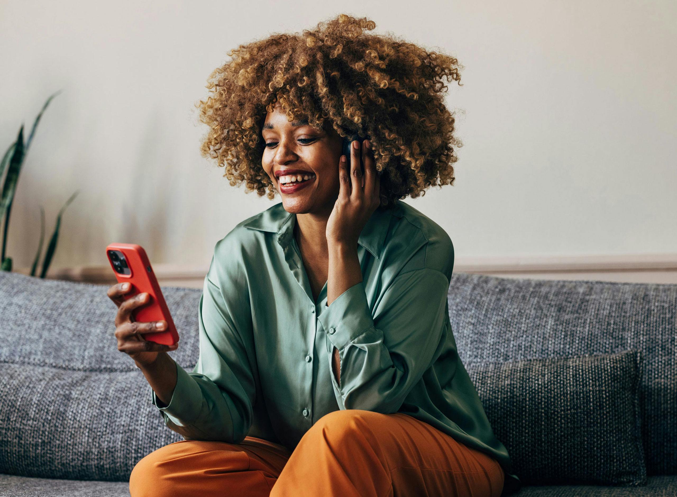 Woman sitting on the sofa looking at her phone while smiling