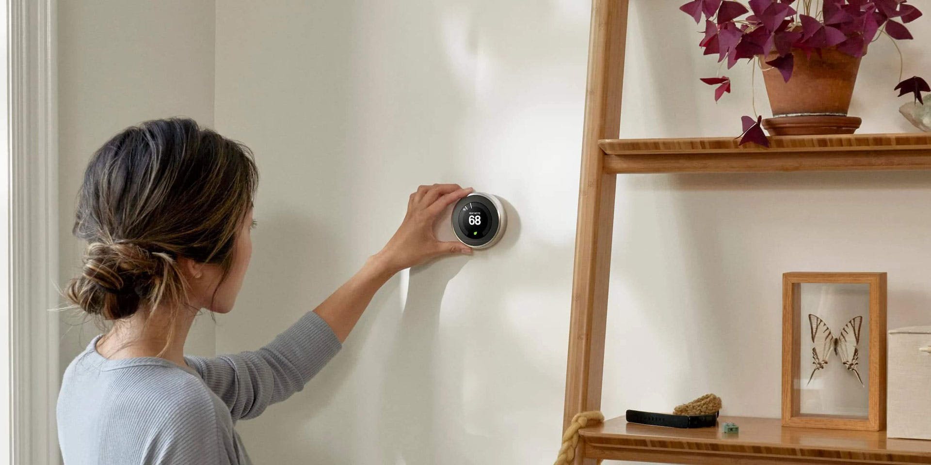 Woman reaching out to the wall to change the temperature on her Smart Thermostat
