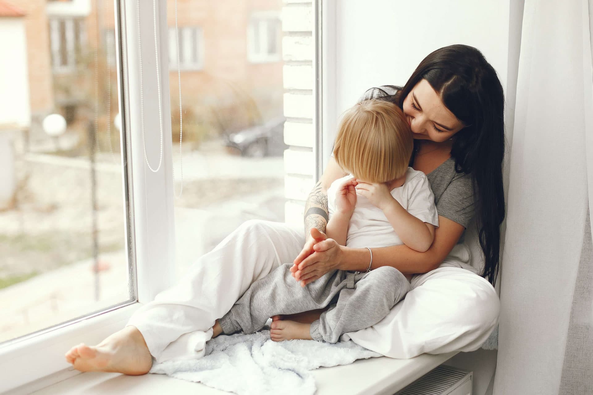 Woman sat next to the window with her young child