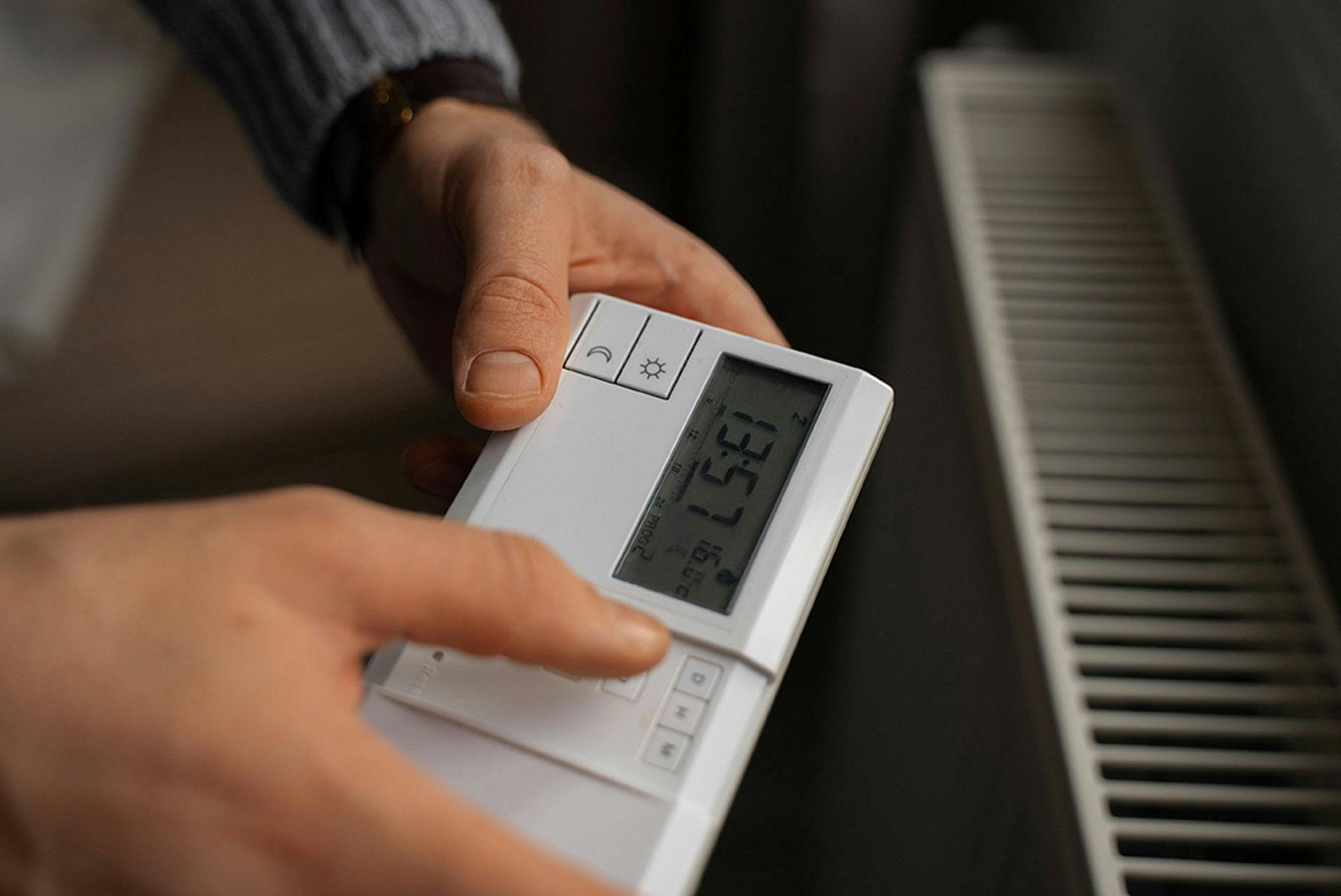 A man holding a handheld device to adjust the temperature of his radiators