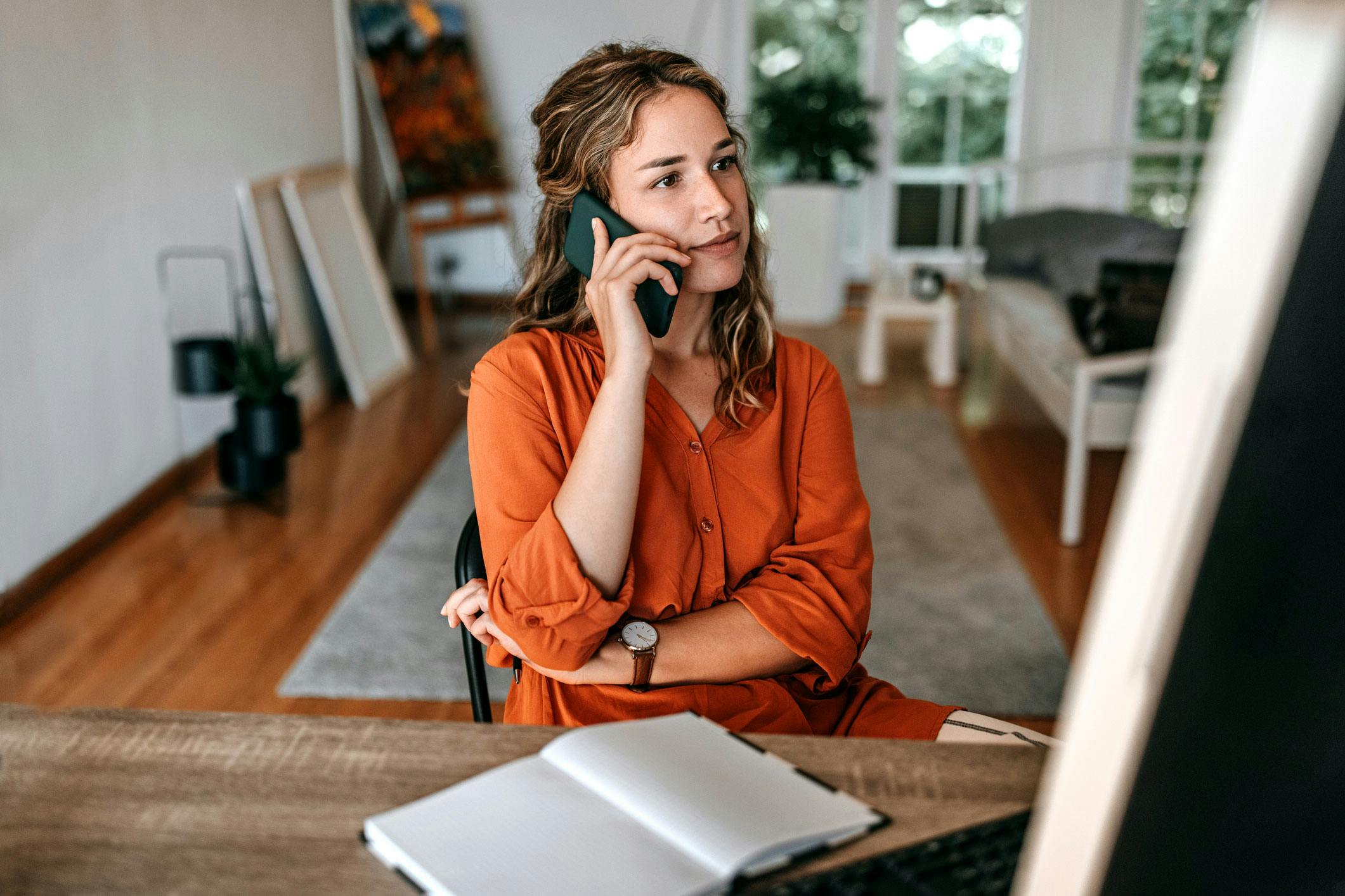 A woman sat at a desk on her phone talking to a Utilita Home Energy Consultant about solar panels.