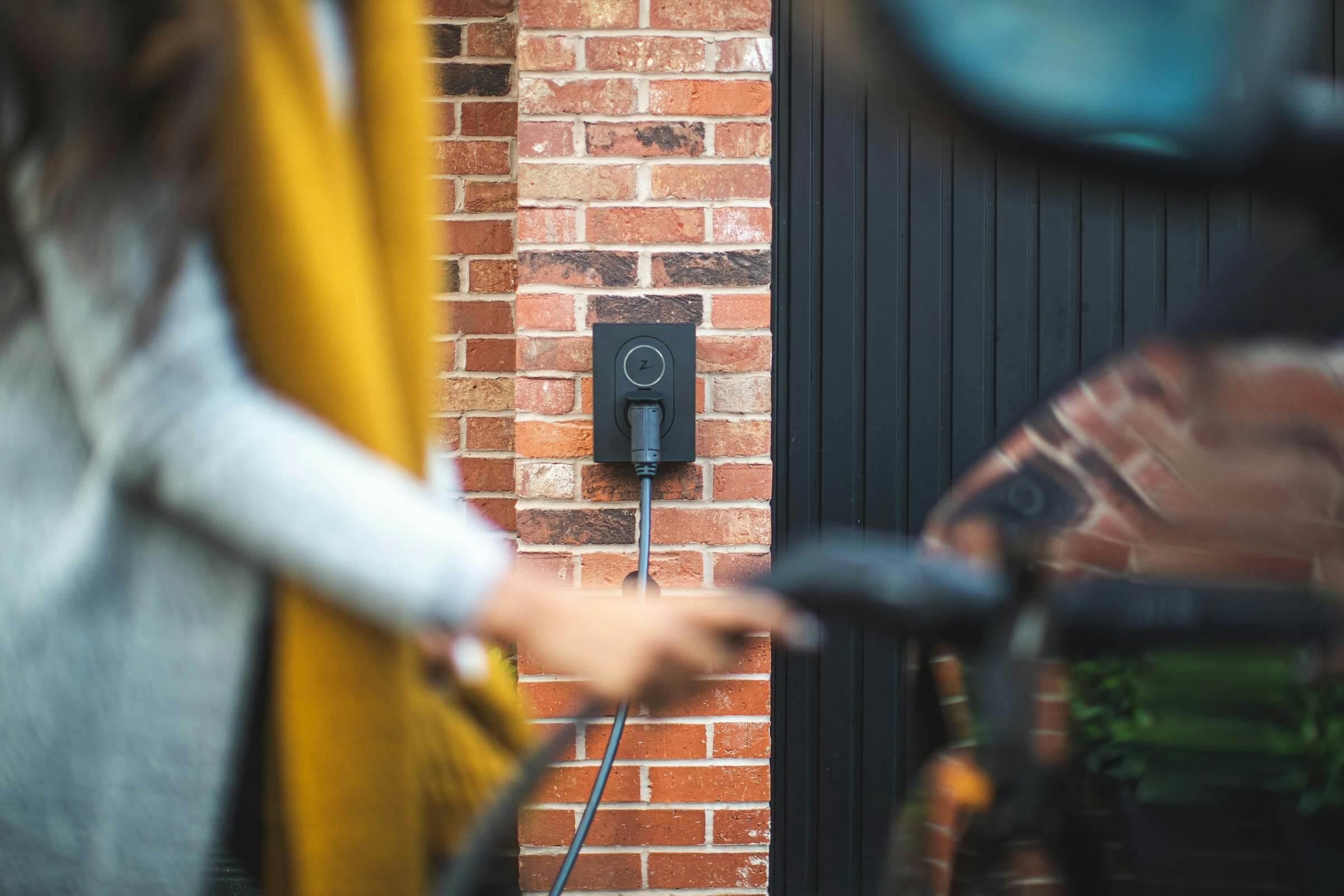 Person charging their car with a wall-mounted personal home EV charger.