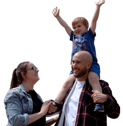A mother & father with their son on his shoulders in front of their house with a 9 panel solar package installed on the roof.