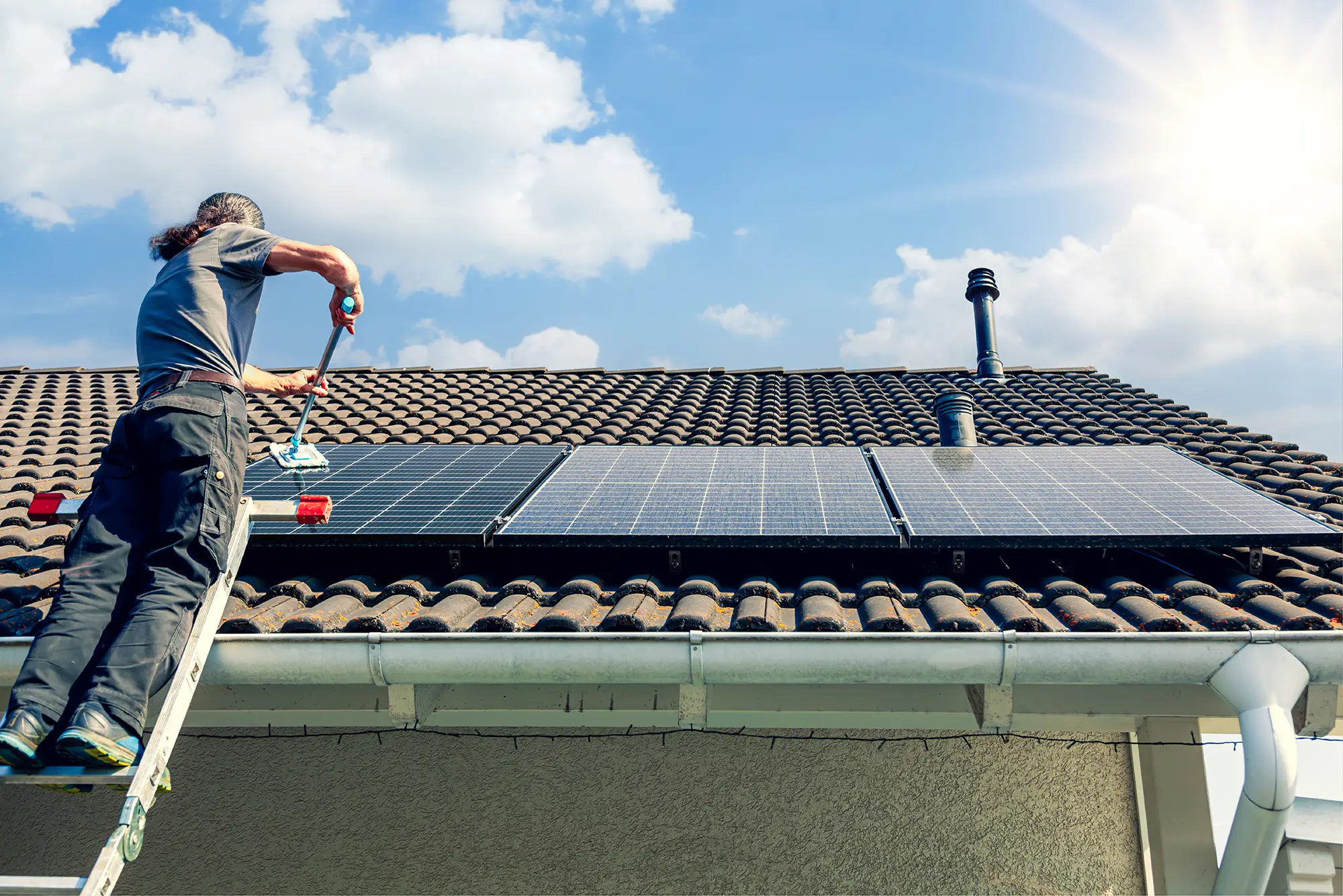 Image of engineer on roof with solar panels, showing how solar panel cleaning can future-proof & maximise energy savings.
