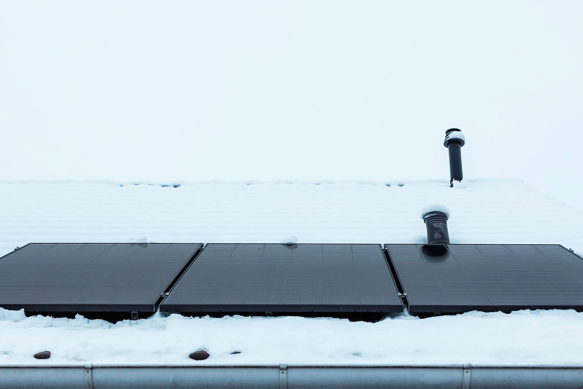 Rooftop solar package on a house surrounded by snow, showing how customers can still reap solar panel benefits in the winter.